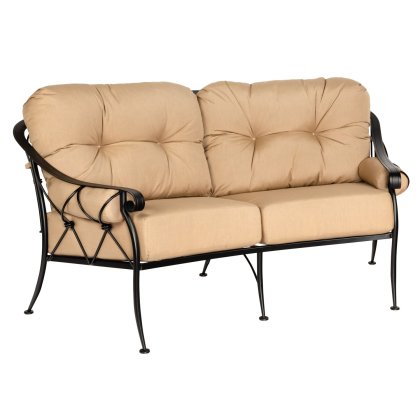 The Derby Crescent Love Seat is a two-seater patio sofa with beige tufted cushions and a black metal frame adorned with elegant swirls and side crisscross patterns.