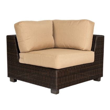 The Montecito Corner Sectional Unit offers a brown wicker outdoor corner chair with beige cushions and sturdy black legs. Its square design ensures comfort with thick cushions, perfect for any patio or garden.