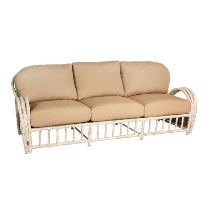 The River Run Sofa features a wicker-style design with a whitewashed frame and three beige, cushioned seats. It showcases smooth curves at the armrests and a slatted base, offering a harmonious blend of classic and contemporary styles.