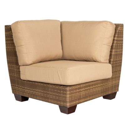 The Saddleback Corner Sectional Unit is a right angle sectional chair with a brown wicker frame, beige cushions, and wooden legs, perfect for outdoor or indoor use.