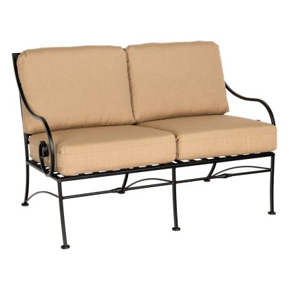 The Sheffield Love Seat is a black metal loveseat featuring decorative scroll designs on the arms and base, complete with thick, beige cushions for comfortable seating for two.