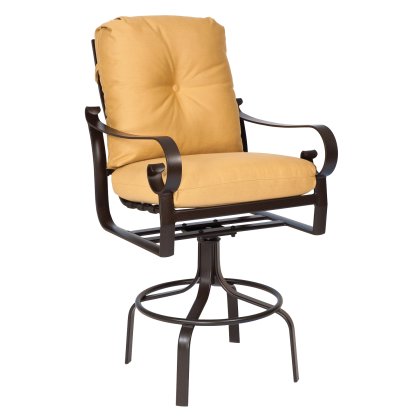 The Belden Cushion Swivel Bar Stool is a brown metal chair with swivel feature, curved armrests, and a circular base. It has a cushioned back and seat upholstered in yellow-orange fabric.