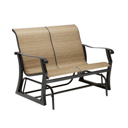 The Cortland Sling Gliding Love Seat features a black metal frame with a beige woven fabric seat and backrest, complete with straight armrests and curved support for gentle rocking.
