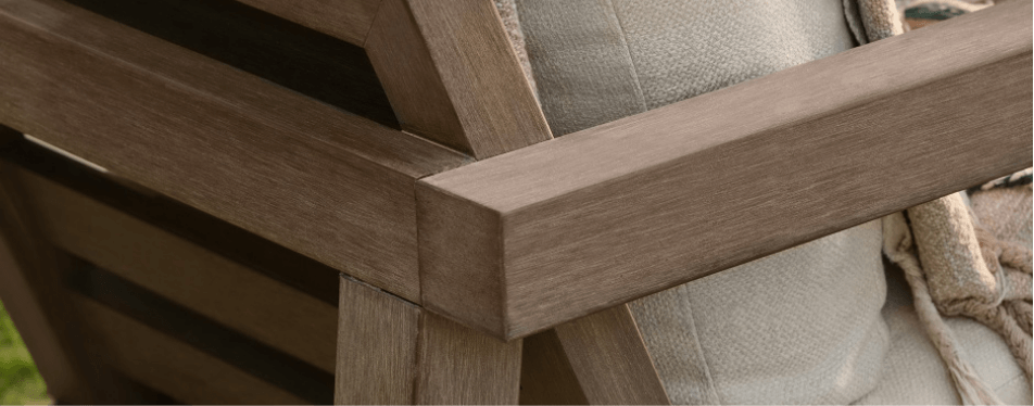 Close-up of a NexTeak armrest on an outdoor chair, paired with a textured beige cushion and tan blanket.